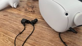 The Final VR3000 earbuds on a table next to a Meta Quest 2 VR headset.