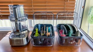 Breville Paradice 16 food processor on a table beside the two storage boxes for its blades and attachments